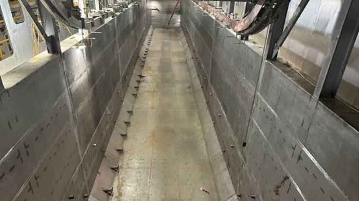 Empty E-coat process tank with metal walls and overhead conveyor equipment