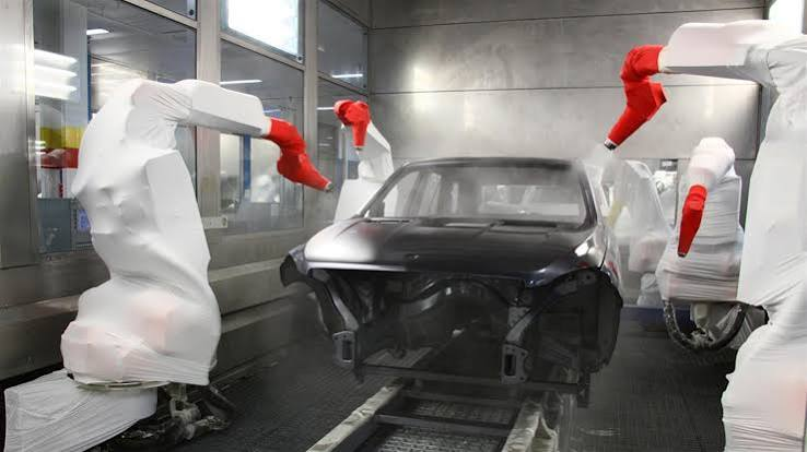 Automotive paint booth with a vehicle body and covered robotic sprayers